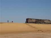 Vlak se pokouší jet pouští. Před ním jdou zaměstnanci a odmetávají písek z kolejí. Poušť Sahara. Egypt.