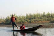 Tradiční pádlování nohou. Muž z kmene Intha na lodi stojí a pomáhá si nohou. Jezero Inle. Myanmar (Barma).